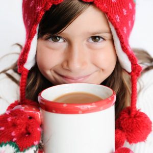 Young girl smiling while holding hot chocolate.